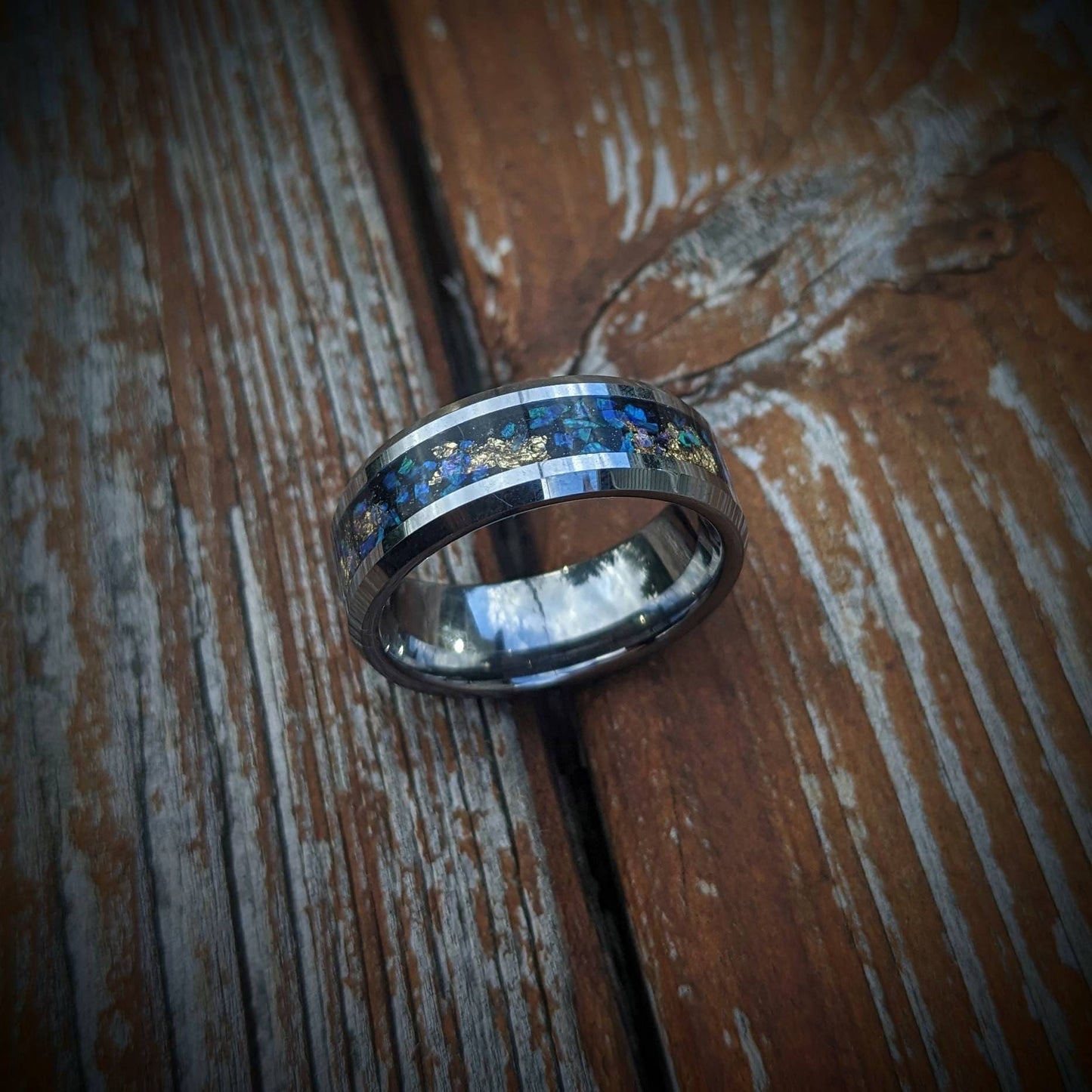 Our galaxy-inspired tungsten ring features luminous blue opals and delicate gold leaf accents set in a polished, durable band. The opals shimmer with changing colors reminiscent of distant galaxies, while the gold leaf adds a touch of luxury. This ring offers a comfortable, snug fit, making it a perfect statement piece or unique everyday accessory. Embrace the magic of the universe and express your one-of-a-kind style with this celestial-inspired jewelry design.