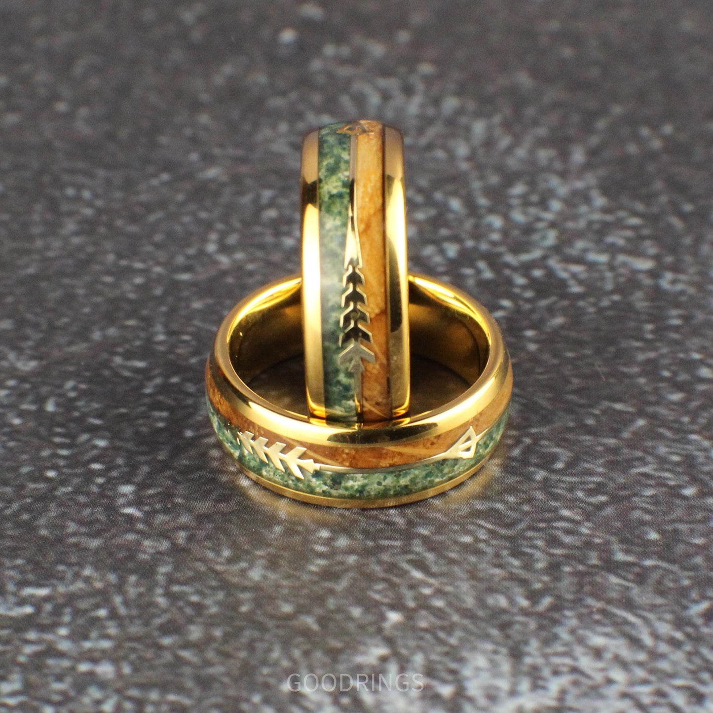 Domed gold band with moss agate and burnt whiskey wood inlay, separated by a gold arrow; stylish ring blending elegance with a natural touch.