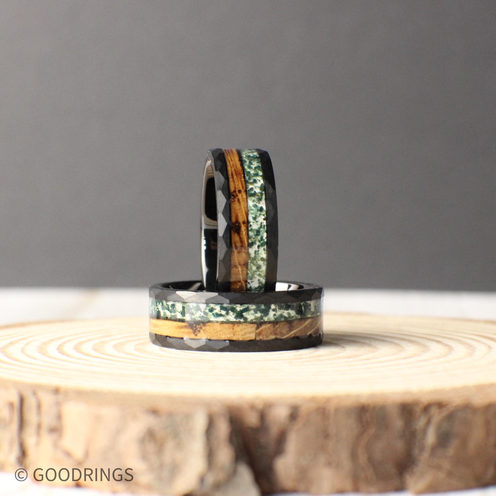 Designed for durability and style, this black hammered tungsten ring features a rich whiskey barrel wood inlay alongside lush green moss agate.