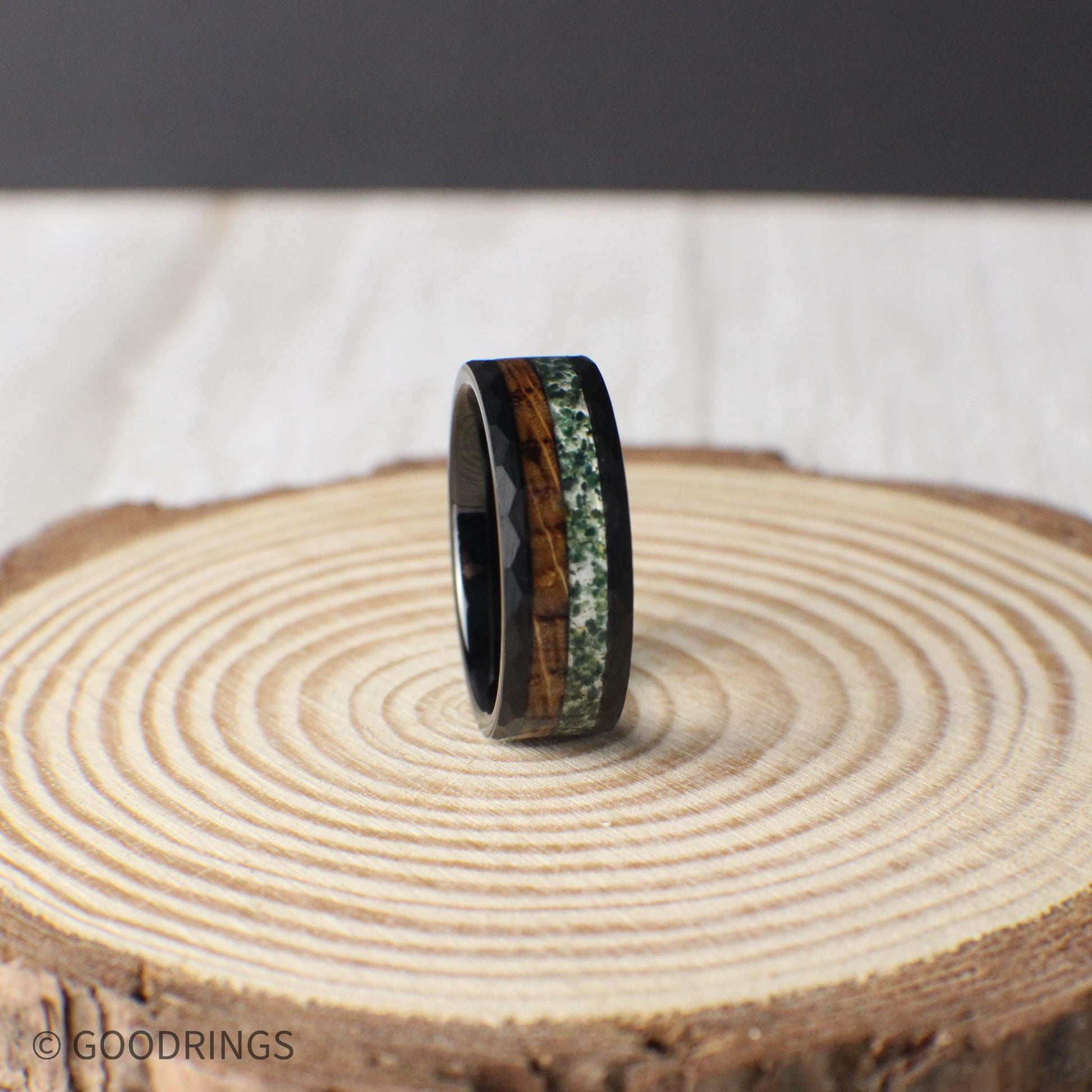 A handcrafted 8mm black tungsten ring with a dual inlay of whiskey barrel wood and moss agate, offering a blend of organic textures and modern design.