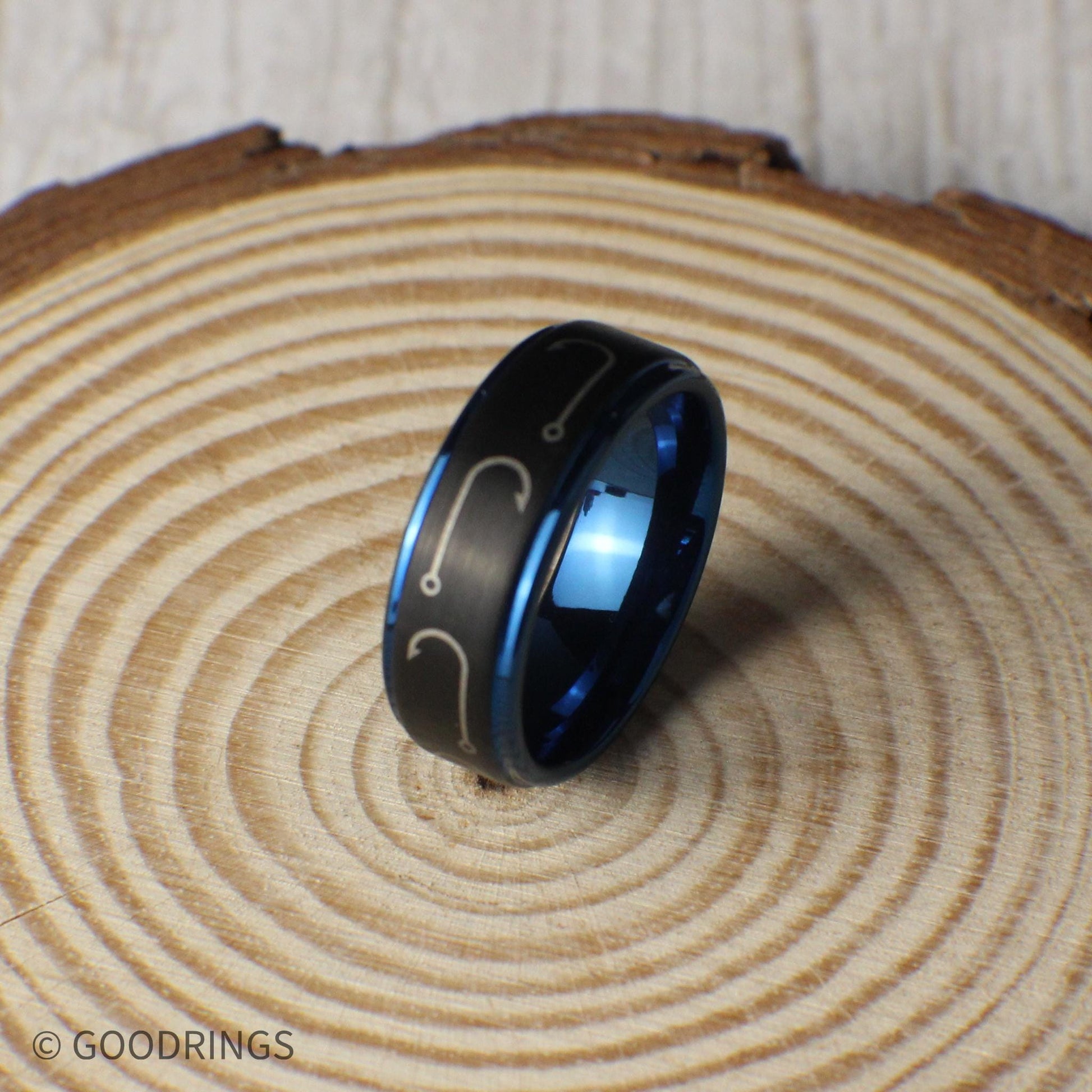 A rugged and stylish black tungsten ring with engraved fishing hooks that wrap around the entire band. The deep blue interior and edges give it a modern, eye-catching look. Made for comfort, this 8mm band is ideal for fishermen, outdoorsmen, and those who love the water. Comes in a premium green and gold ring box inside a gift box, with a ring sizer and silicone ring included. Free resizing and returns offered.