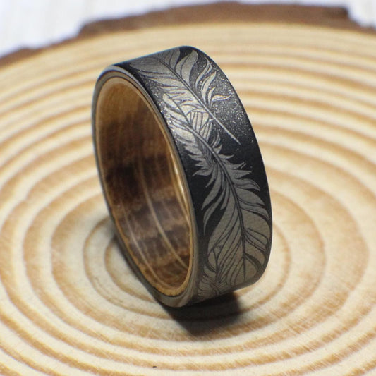 Engraved tungsten ring with seamless feather design and whiskey barrel wood interior, 8mm wide.