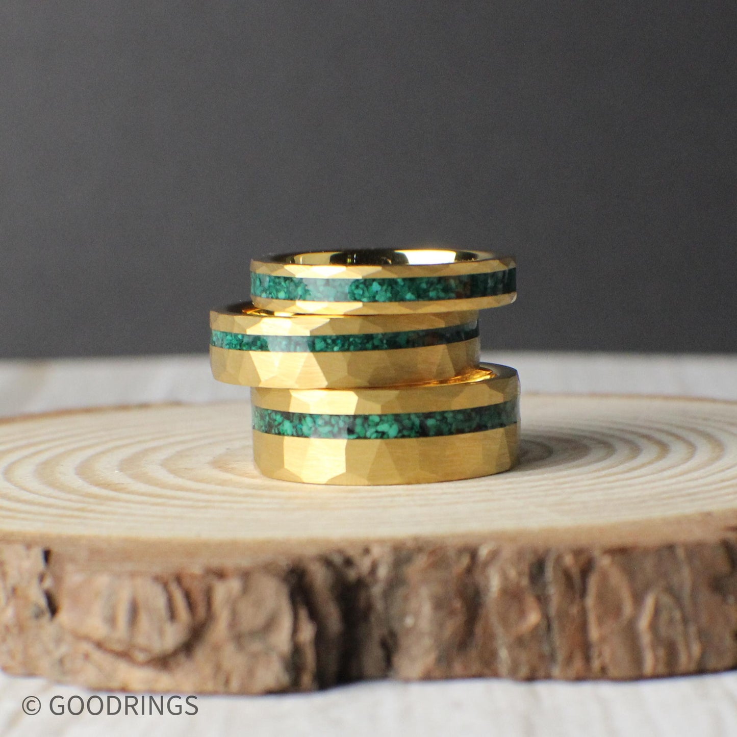 The 8mm, 6mm, and 4mm Verdant Edge rings stacked together, showing their width differences and unified design. The hammered gold texture and offset crushed malachite inlay align beautifully across all sizes, emphasizing the versatility and craftsmanship of the ring. A striking presentation for those considering multiple size options or a matching set.