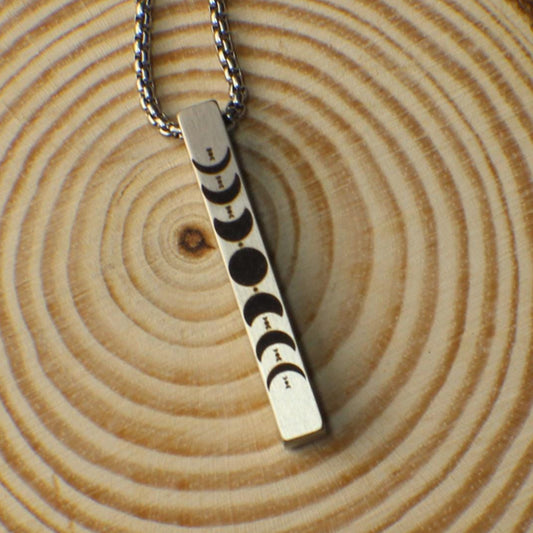 This stainless-steel bar necklace features a detailed engraving of the moon phases on the front, symbolizing change and cycles. Made with a brushed finish for a sleek, modern look, the pendant measures 1.5 inches and hangs from a 22-inch box chain. The left, right, and back sides of the pendant can be personalized with names, dates, or messages, making it a meaningful gift for space lovers or anyone who appreciates celestial beauty.