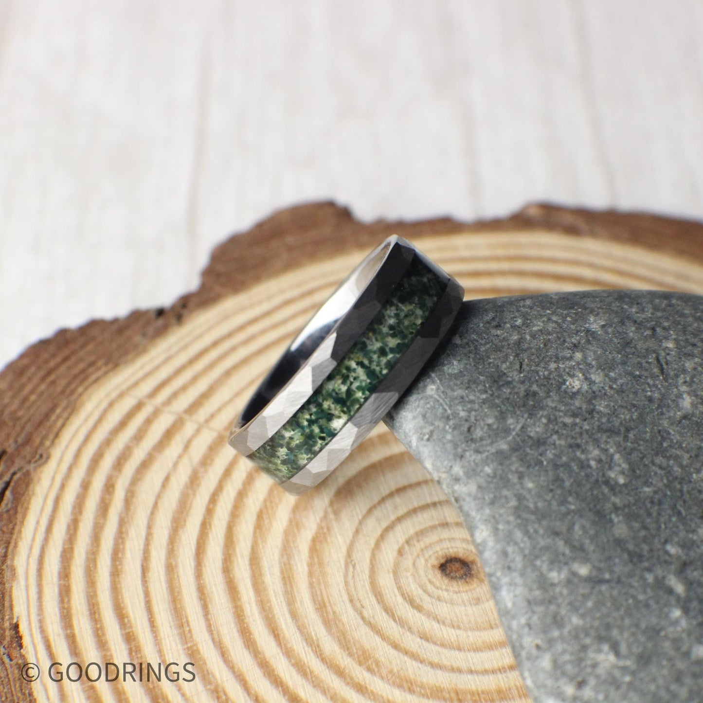 Faceted tungsten ring for men with genuine moss agate inlay. Eco-conscious wedding band choice with rich green tones and modern hammered edges.