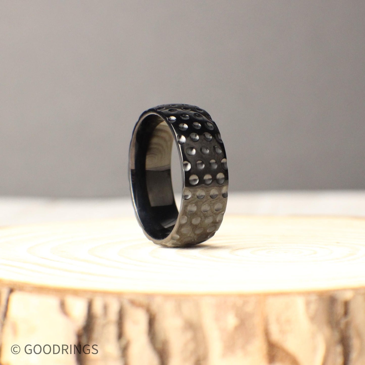 Sporty titanium men’s ring with 8mm wide golf ball dimples across the band, crafted for those who value both strength and individuality, presented in a polished black finish, perfect for golfers, athletes, or anyone looking for a stylish, durable wedding band with a unique textured design.