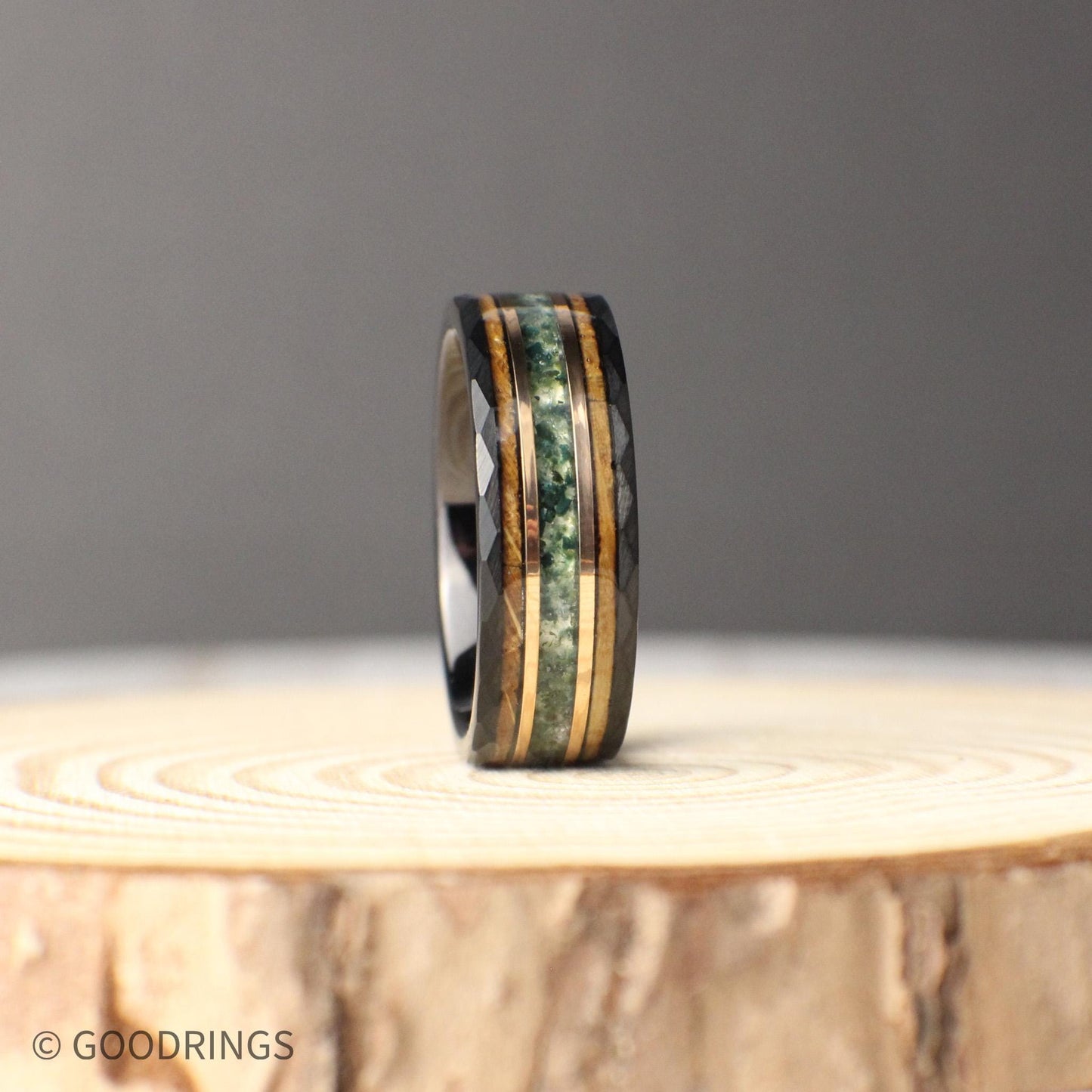 Modern and rustic 8mm hammered black tungsten ring featuring inlays of moss agate, 18K rose gold, and whiskey barrel wood. The earthy tones of agate, the warmth of rose gold, and the rich whiskey wood create a balanced design full of personality. Durable and crafted for daily wear, this comfort-fit ring is a striking choice for a wedding band, anniversary gift, or a personal keepsake that stands out.
