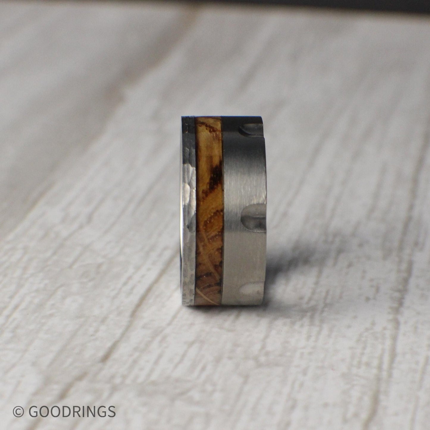 Masculine 10mm tungsten ring styled after the chamber of a revolver, featuring recessed grooves for a unique, rugged finish. A striking inlay of charred whiskey barrel wood runs through the band, symbolizing tradition and heritage while adding natural character. Perfect for weddings, anniversaries, or as a bold statement piece, this durable comfort-fit band combines grit, style, and individuality.