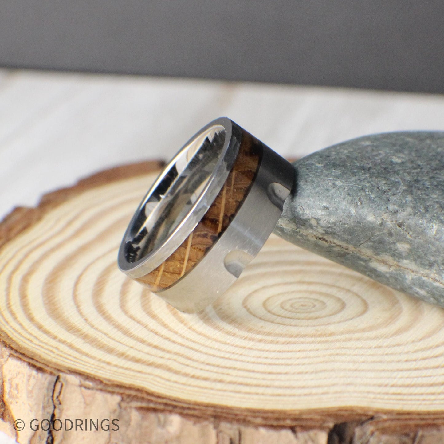 A bold 10mm tungsten ring crafted to capture the style of a revolver chamber, complete with recessed grooves that add toughness and depth. The inlay of charred whiskey barrel wood creates a warm, rustic contrast to the modern brushed tungsten. Durable, comfortable, and full of character, this ring is ideal for weddings, anniversaries, or anyone seeking a statement piece that blends heritage with strength.