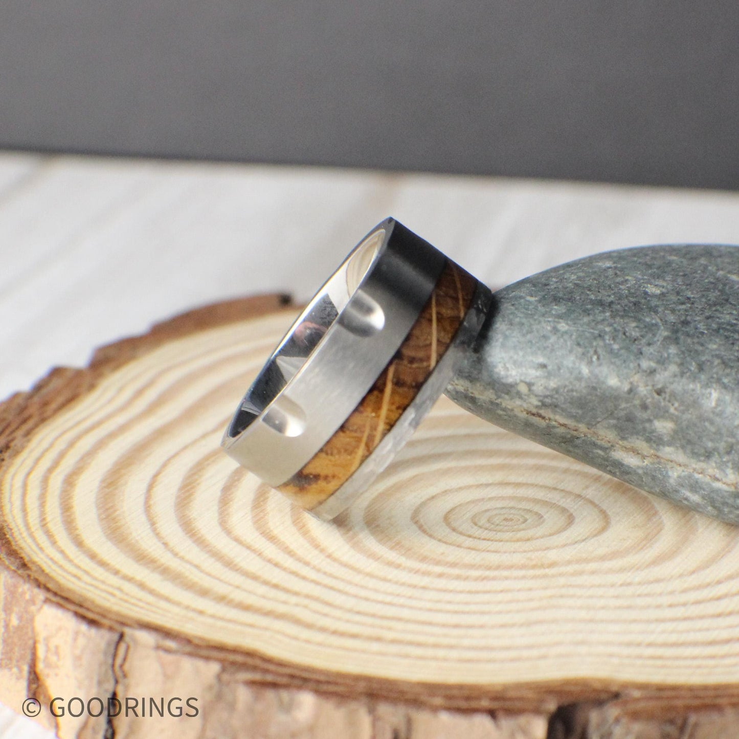 Rugged 10mm tungsten band designed with revolver-inspired grooves, giving it a powerful, industrial look. The ring features a rich inlay of charred whiskey barrel wood, blending natural warmth with the durability of tungsten. This comfort-fit ring makes a striking wedding band or everyday accessory for those who value distinctive design and meaningful detail, representing resilience and bold style.