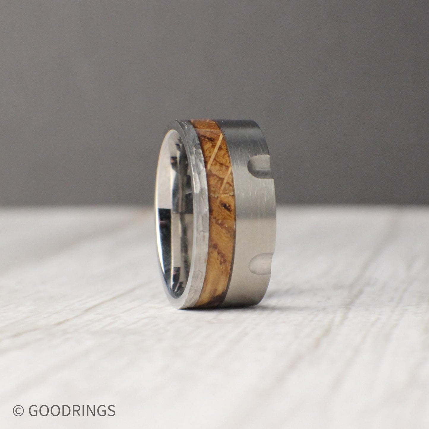 10mm tungsten wedding band inspired by the mechanical design of a revolver, featuring detailed grooves carved into the brushed metal band. The centerpiece is an inlay of charred whiskey barrel wood, showcasing natural texture and heritage against the sleek durability of tungsten. Rugged yet refined, this masculine ring makes a unique choice for weddings, anniversaries, or everyday wear.