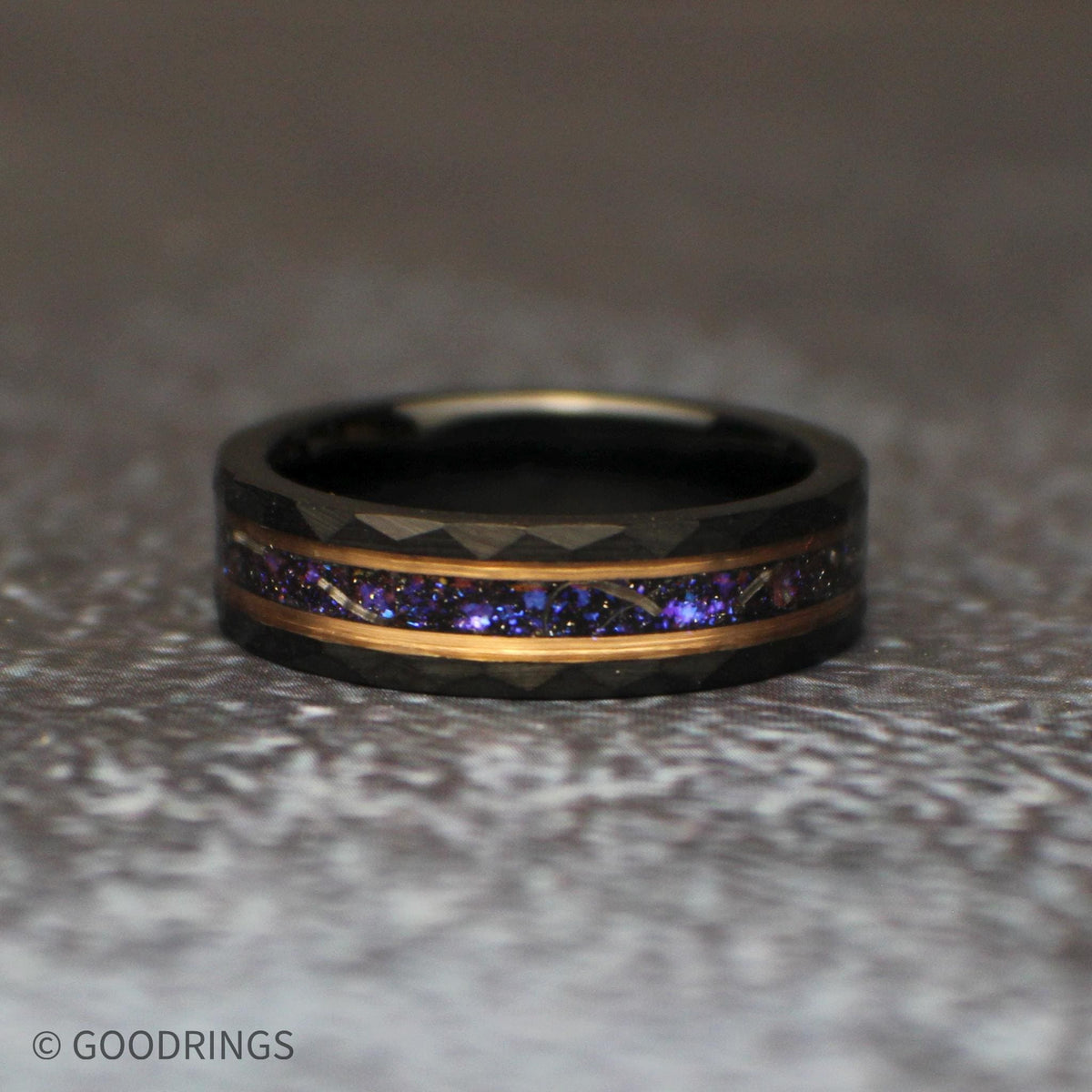 Close three-quarter view of the galaxy wedding band, showing the purple and blue inlay framed by rose-gold-toned lines and textured black tungsten.