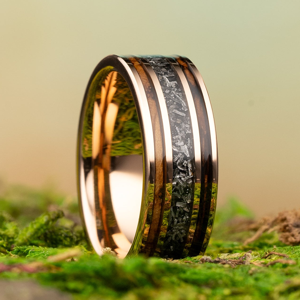 Gold and black ring on a mossy surface with a blurred natural background