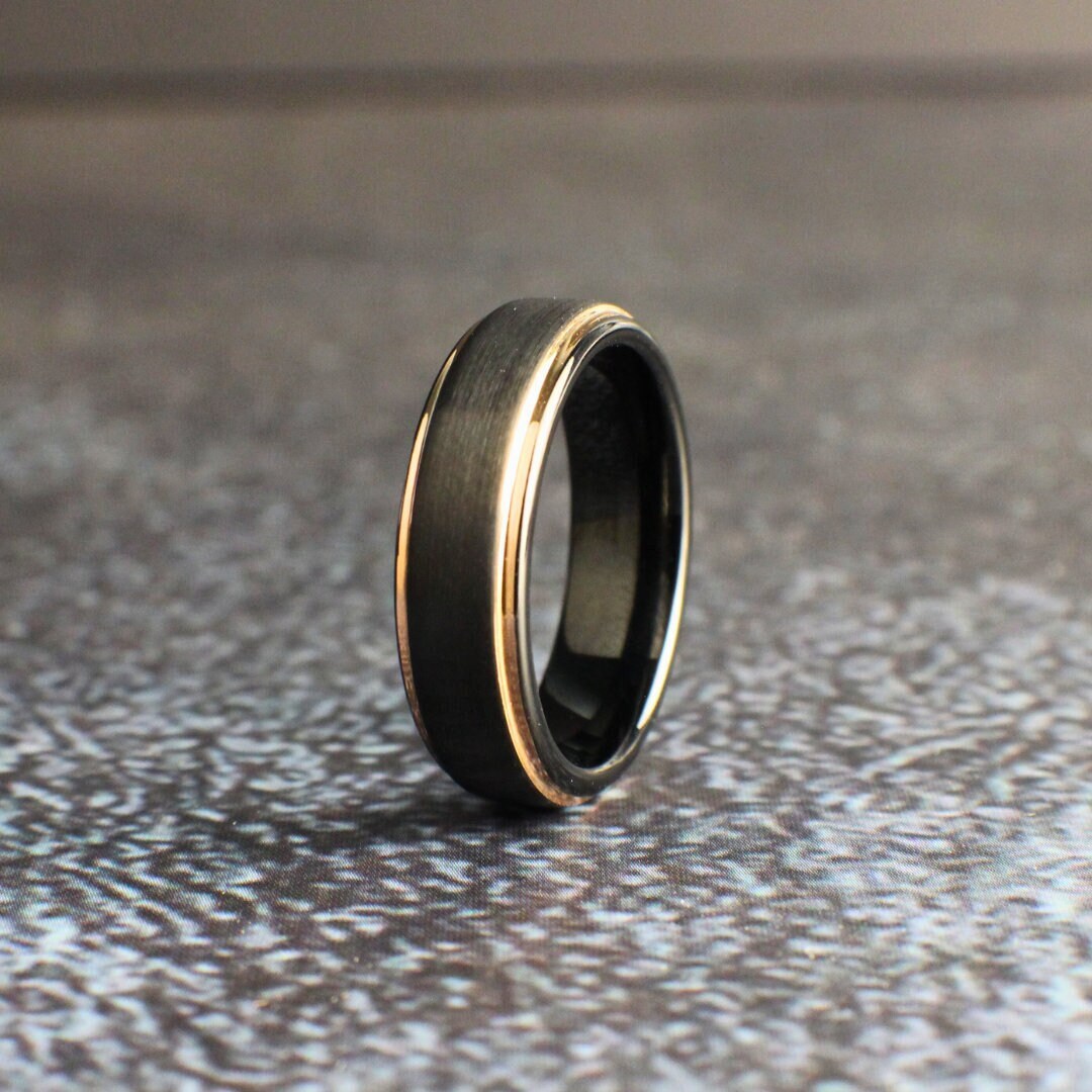 Tungsten wedding ring with a brushed finish and rose gold edges.