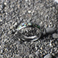 A polished silver ring, 6mm wide, featuring a black inlay layered with shimmering white opals.
