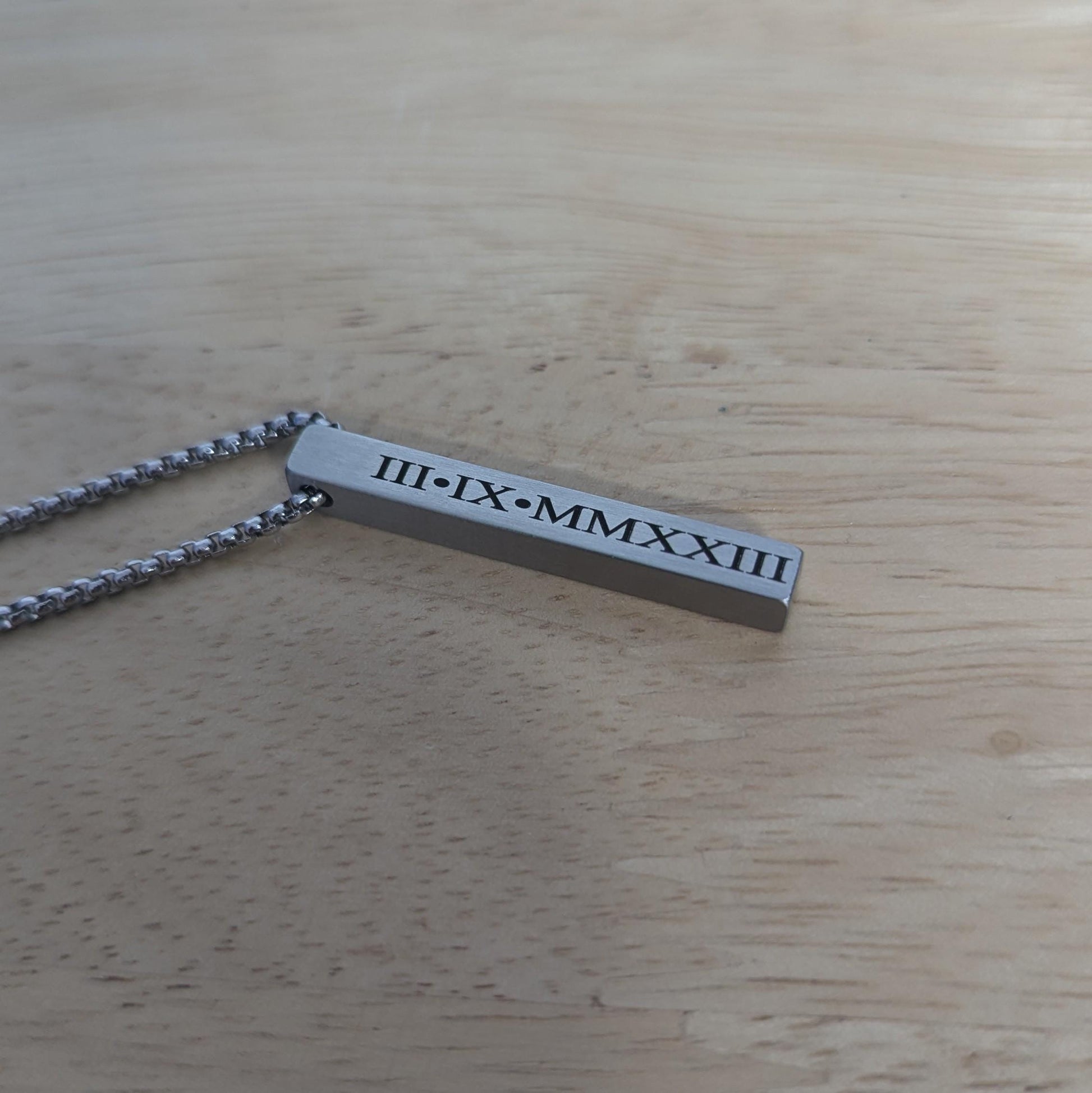 Close-up of a rectangular stainless steel bar pendant with a brushed finish, hanging from a sleek 22-inch box chain, customizable with meaningful engravings.