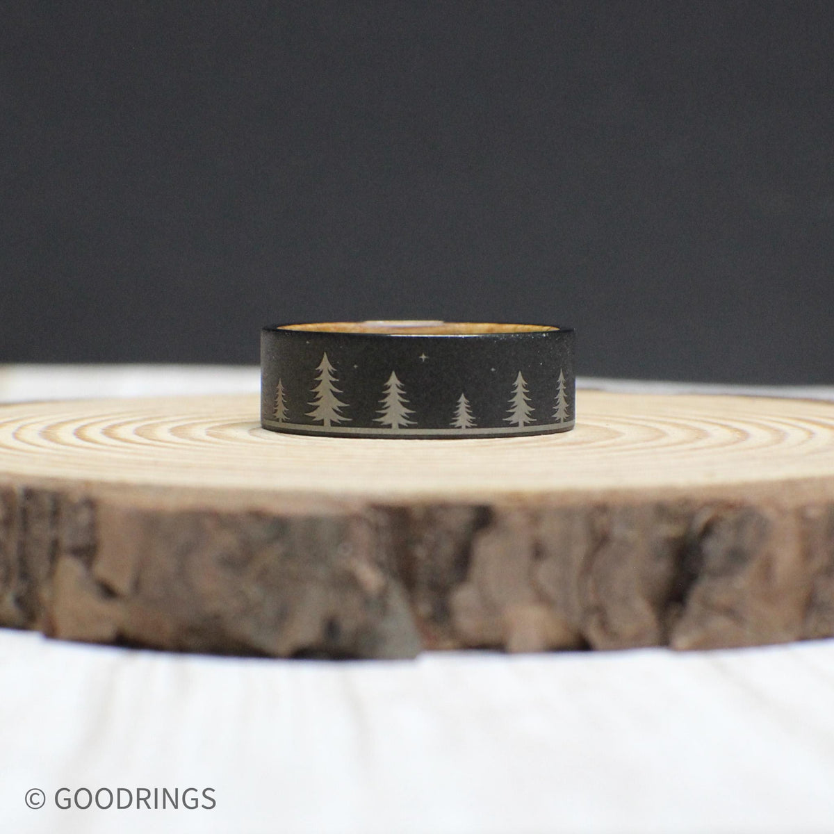 Tungsten and whiskey barrel wood ring showcasing its engraved forest design and warm wooden interior.