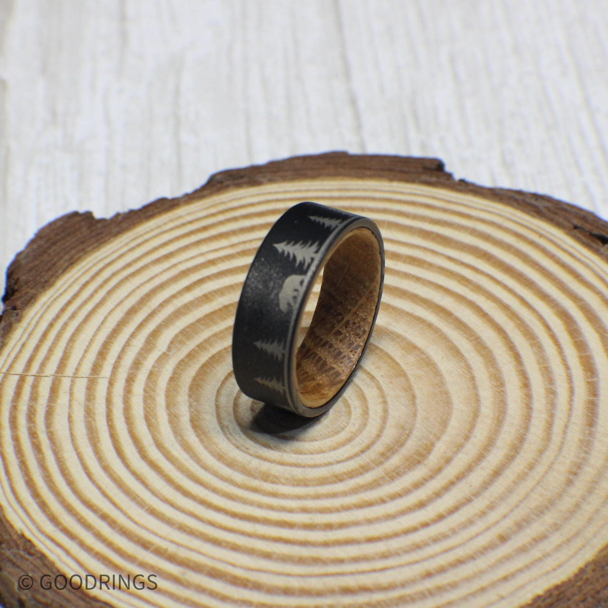 8mm tungsten ring with a whiskey barrel wood interior, beautifully engraved with a nature-inspired scene of a tent, trees, a bear, and a starry sky.
