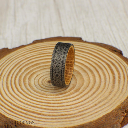Polynesian-inspired tungsten ring with a seamless engraved design and a warm whiskey barrel wood interior for contrast.
