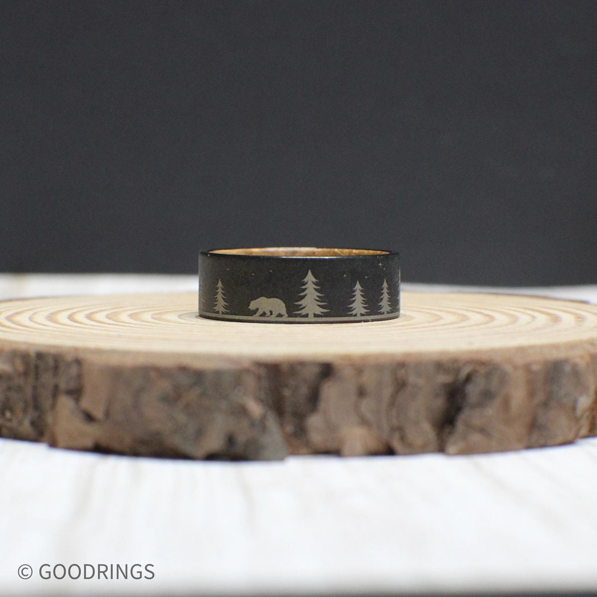 Wedding ring highlighting the intricate forest engraving on durable tungsten and the rich whiskey wood lining inside.