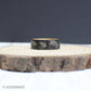 A unique fly fishing ring made from tungsten with engraved lure designs and a whiskey barrel wood interior.