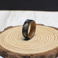A durable tungsten ring featuring engraved fly fishing lures and a rustic whiskey barrel wood interior.