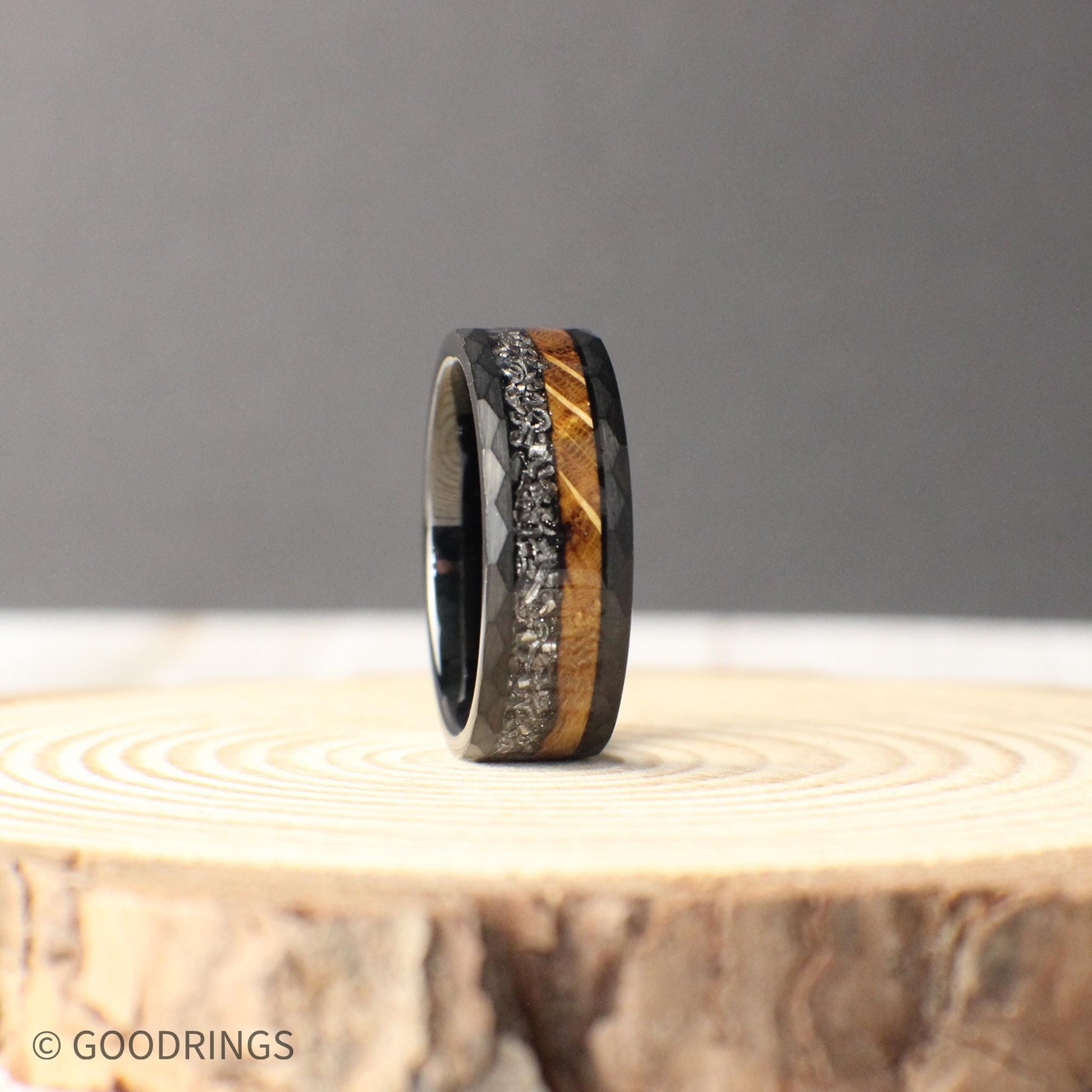 An 8mm hammered tungsten ring with a dual inlay of burnt whiskey barrel wood and genuine Muonionalusta meteorite, blending rugged earthiness with cosmic wonder.