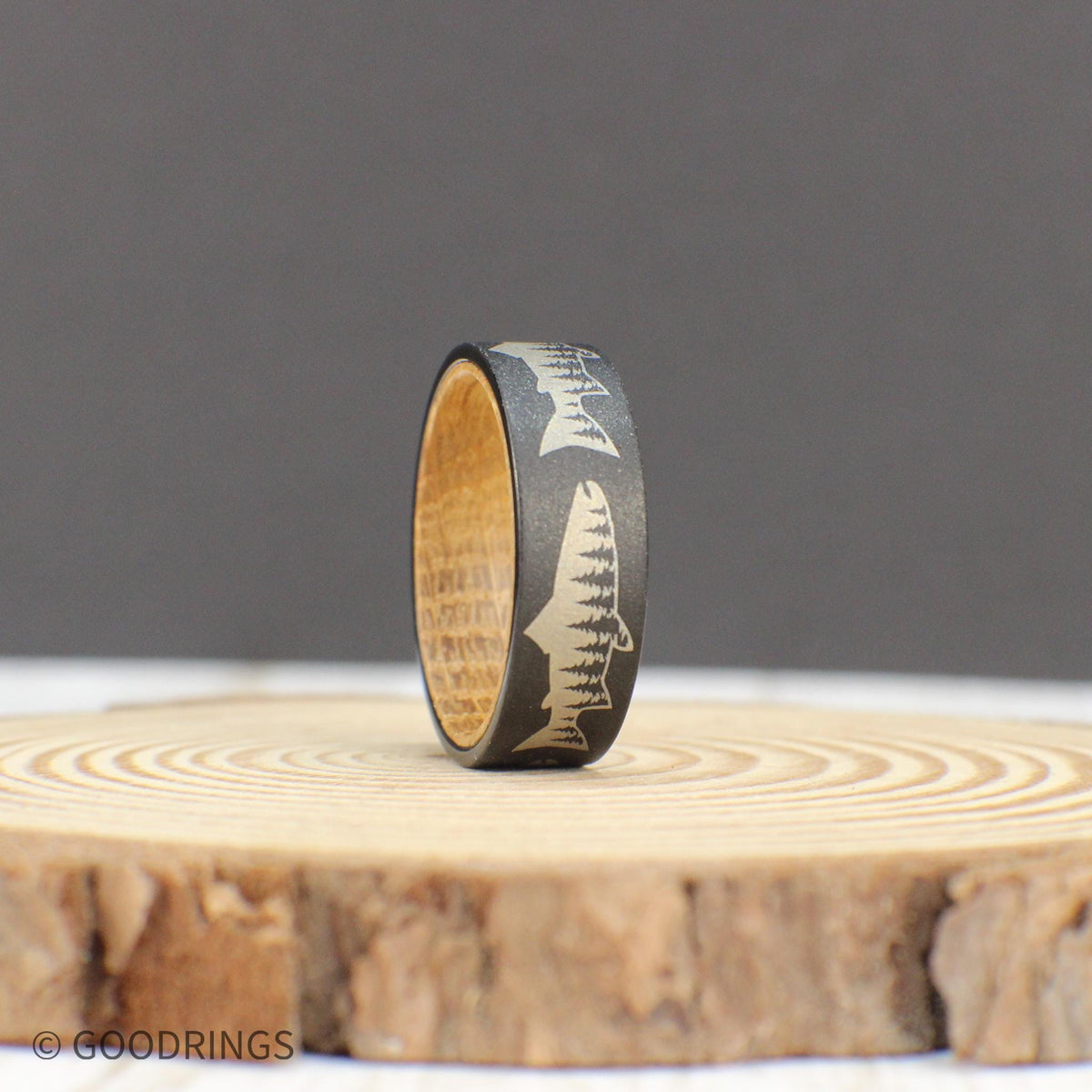 Nature-inspired tungsten ring featuring a salmon engraving with a tree line inside, complemented by a whiskey wood liner.