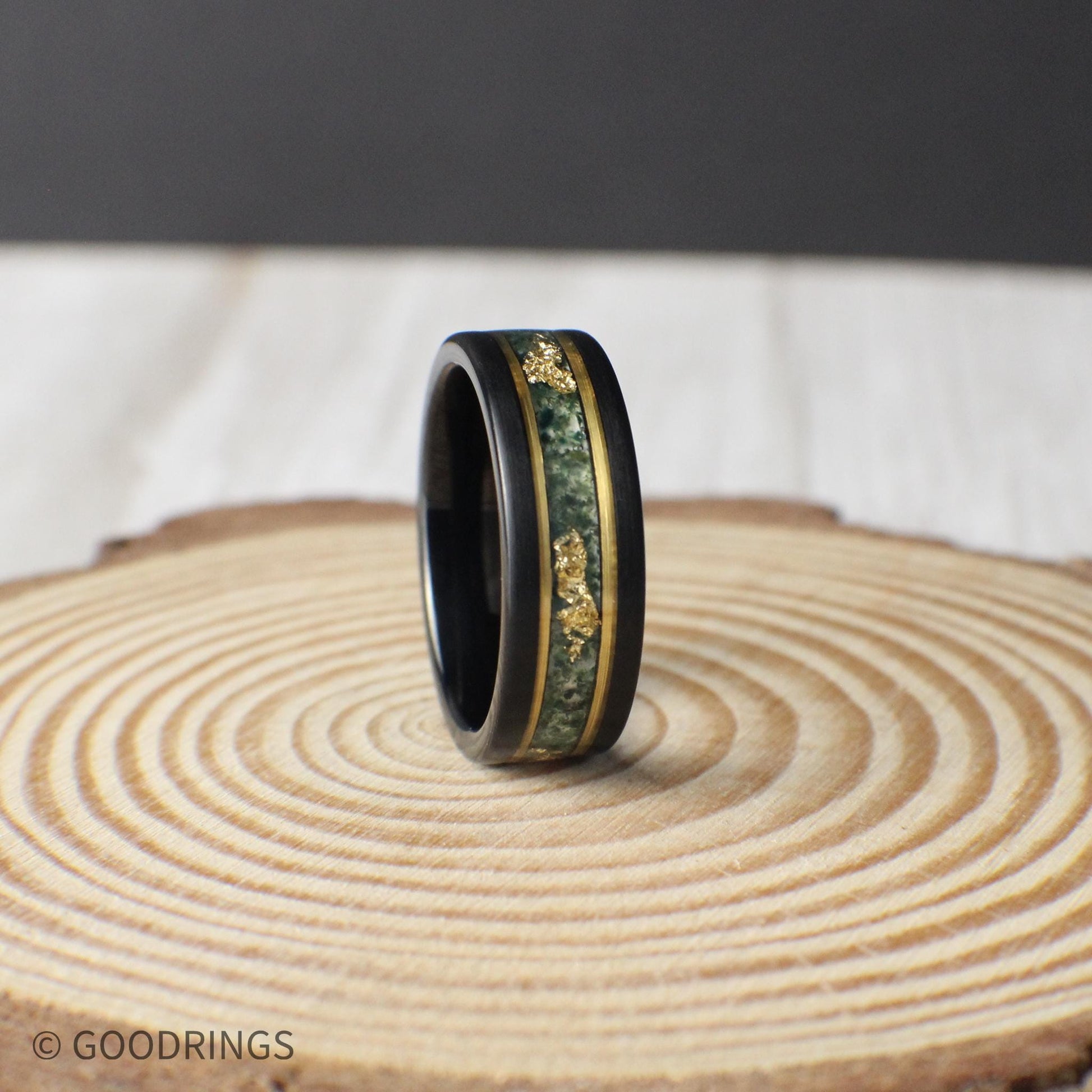 Black tungsten ring with moss agate inlay and gold leaf highlights, framed by gold lines. Each agate piece is unique, ensuring a one-of-a-kind design. Comes with a ring box, silicone ring, and ring sizer, plus lifetime warranty and free exchanges.