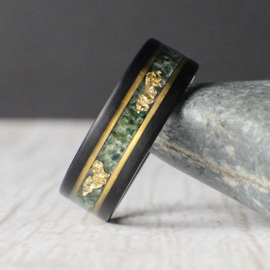 Black tungsten ring featuring a moss agate inlay with unique patterns and delicate gold leaf accents, bordered by gold lines for a refined finish. Includes a gift box, ring sizer, and silicone ring, with lifetime warranty and free exchanges.