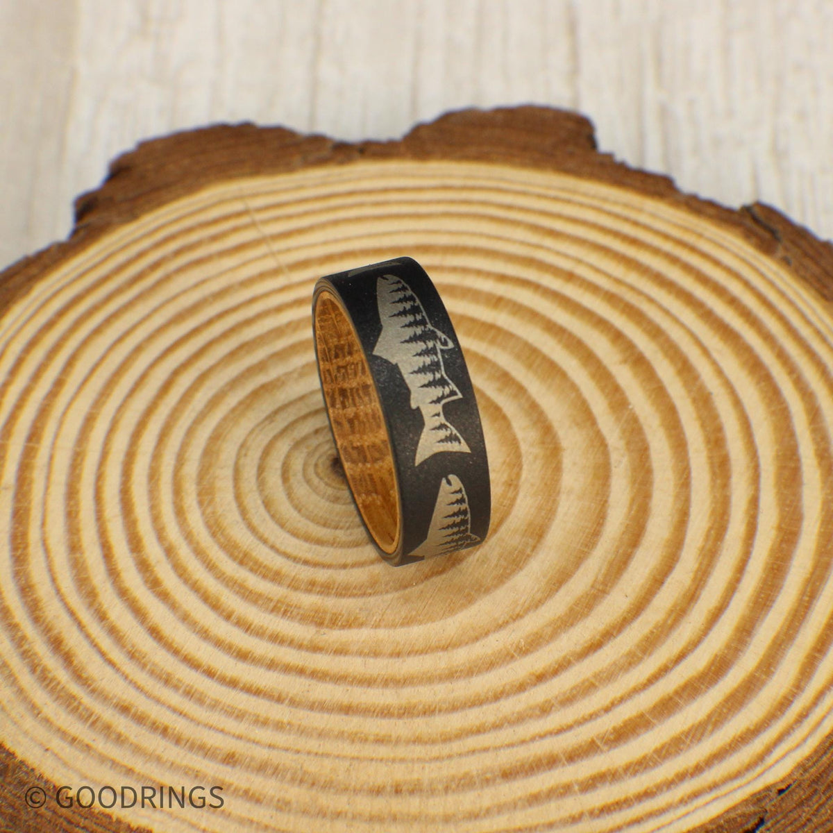 Sandblasted tungsten ring with detailed salmon and tree line engraving, lined with whiskey barrel wood.