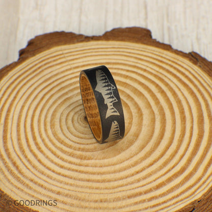 Sandblasted tungsten ring with detailed salmon and tree line engraving, lined with whiskey barrel wood.