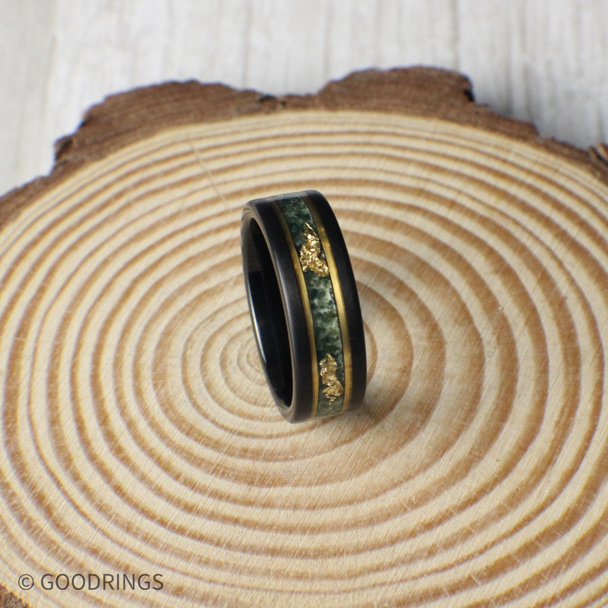 Striking 8mm black tungsten ring with moss agate and gold leaf inlay, bordered by gold lines for added elegance. Includes a gift box, silicone ring, and ring sizer. Covered by a lifetime warranty with free exchanges and easy returns.