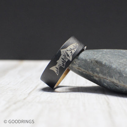 This tungsten ring features an engraved fish with a mountain and tree design on the exterior and smooth whiskey barrel wood lining inside. The comfort fit ensures it can be worn daily, making it a great gift for outdoor enthusiasts.