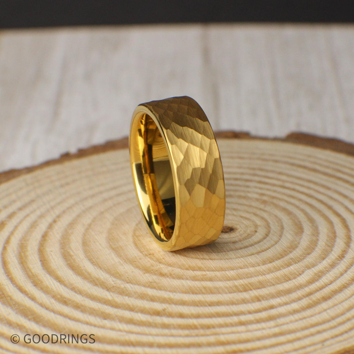 Close-up of an 18K gold plated tungsten ring, 8mm wide with a distinctive hammered finish. Designed for men or women who prefer subtle sophistication and long-lasting quality. The gold plating adds warmth to the rugged texture, while the included silicone band and ring box enhance the overall value. Lifetime warranty, free returns, and exchanges make this an easy, confident choice.