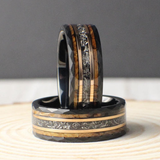 A handcrafted men’s ring made from black tungsten with a rugged hammered finish. It features an inlay of genuine meteorite, accented by rose gold lines and burnt whiskey barrel wood. This unique combination blends durability with striking design, making it ideal for weddings, anniversaries, or as a statement piece for someone who appreciates natural materials and modern style.