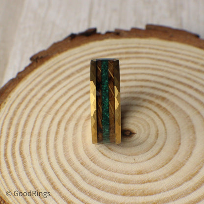 A nature-inspired tungsten ring with a gold hammered finish, offering strength and unique style. It features a dual inlay of burnt whiskey barrel wood and crushed moss agate, providing a mix of deep wood grain and rich green tones. Perfect for weddings, anniversaries, or everyday wear, this 6mm or 8mm ring stands out with its bold texture and natural details. A great choice for anyone who loves rustic, earthy designs.