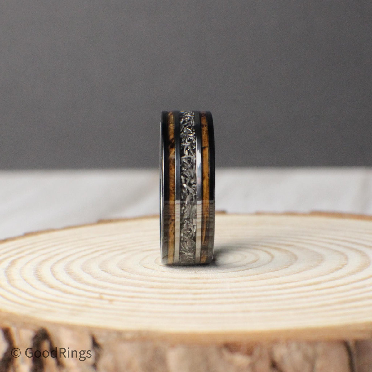 This 8mm tungsten ring is a meaningful and masculine choice for a wedding band or anniversary gift. It features an inlay of burnt whiskey barrel wood, with a bold meteorite line down the center, bordered by clean silver accents. The combination of wood, metal, and stone gives this ring a rich, layered look that symbolizes lasting strength and unity—an ideal gift for a loved one or a commitment to forever.