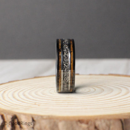 This 8mm tungsten ring is a meaningful and masculine choice for a wedding band or anniversary gift. It features an inlay of burnt whiskey barrel wood, with a bold meteorite line down the center, bordered by clean silver accents. The combination of wood, metal, and stone gives this ring a rich, layered look that symbolizes lasting strength and unity—an ideal gift for a loved one or a commitment to forever.