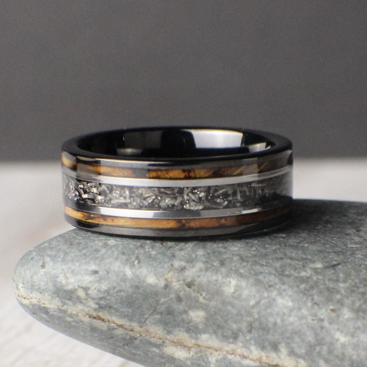 This 8mm tungsten ring is a powerful wedding or anniversary band featuring a burnt whiskey barrel wood inlay with a striking meteorite center line. Silver accents on either side of the meteorite add contrast and detail, creating a refined and symbolic design. A durable and meaningful choice for weddings, promises, or gift-giving, this ring blends natural warmth with space-born material in a unique and lasting statement.