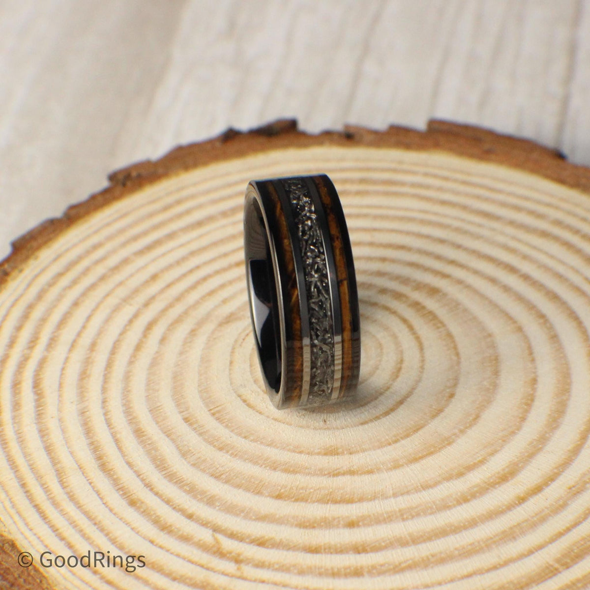 This men's 8mm tungsten ring is designed with commitment in mind. It features an inlay of burnt whiskey barrel wood, intersected by a center line of real meteorite. Silver lines frame the meteorite, adding structure and contrast. Ideal as a wedding ring, promise ring, or anniversary gift, this band represents strength, passion, and the beauty of natural elements—perfect for marking a meaningful chapter.
