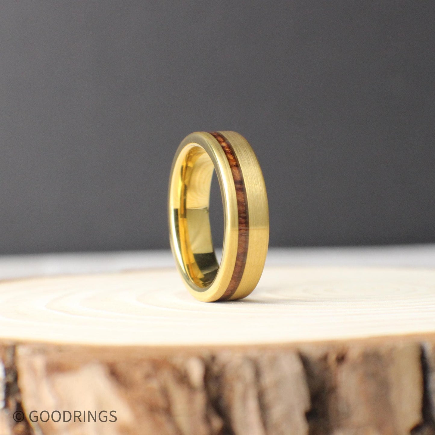 A gold-plated tungsten men’s ring with an offset Hawaiian Koa wood inlay. The rich reddish wood contrasts beautifully with the brushed gold finish. The 6mm wide band is designed for comfort and strength, perfect for weddings or everyday wear. Durable, stylish, and meaningful.