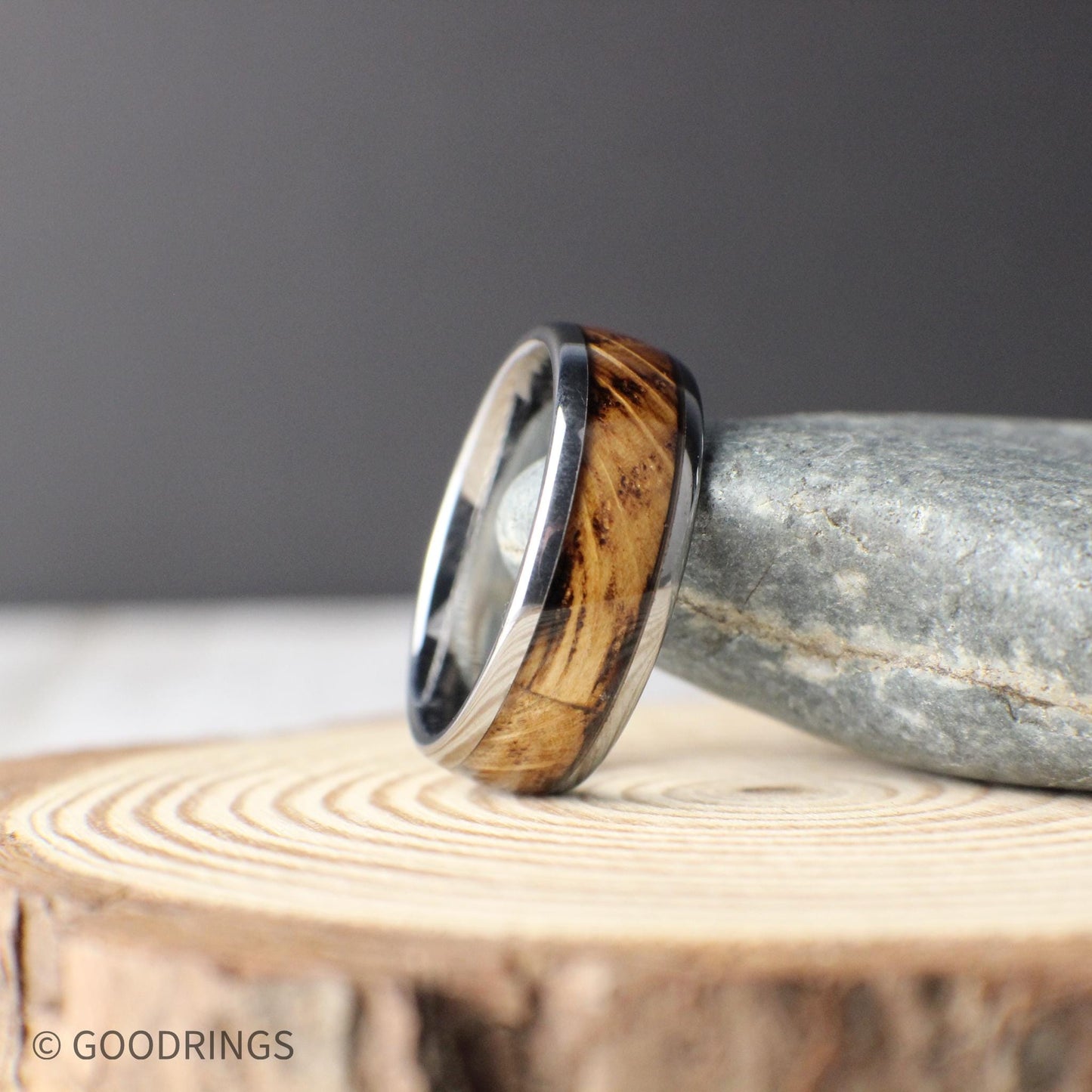 Close-up of a domed tungsten ring with whiskey wood inlay. The natural grain of the wood contrasts with the polished tungsten edges, creating a unique blend of rugged and refined. Ideal for men seeking a meaningful and masculine wedding band.