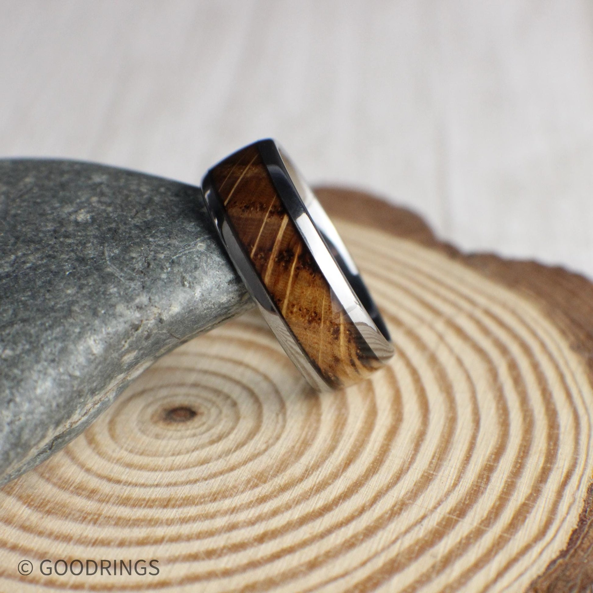 Whiskey-inspired men’s ring crafted from polished tungsten carbide with a domed profile and a bold wood inlay. This comfort-fit band showcases the charm of reclaimed whiskey barrels, offering a masculine and meaningful piece for grooms or collectors.