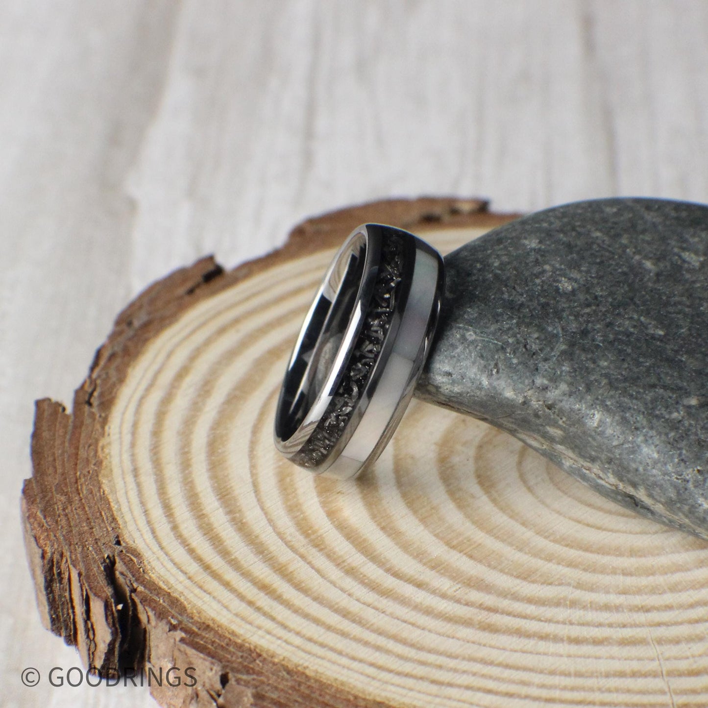 Close view of a men’s tungsten wedding band with cosmic meteorite and shimmering moonstone inlays. Each ring is unique and built with a comfort fit interior. Backed by a lifetime warranty, free exchanges, and free returns for a stress-free shopping experience.