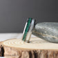 A men’s tungsten wedding band featuring crushed malachite and moonstone inlays. The natural green swirls of malachite add an organic, earthy texture, while the moonstone provides a polished, luminous accent. This domed comfort-fit tungsten ring is highly scratch-resistant, combining strength and elegance in a timeless design. Ideal for weddings, anniversaries, or as a meaningful gift for someone special.