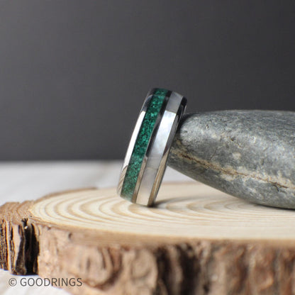 Close-up view of a domed tungsten ring inlaid with crushed malachite and luminous mother of pearl. The deep green patterns of the malachite contrast with the glowing white tones of the mother of pearl, creating a ring that feels earthy yet modern.