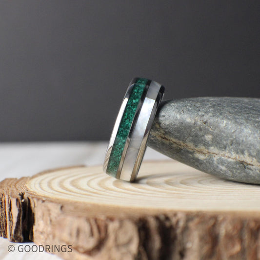 Close-up view of a domed tungsten ring inlaid with crushed malachite and luminous mother of pearl. The deep green patterns of the malachite contrast with the glowing white tones of the mother of pearl, creating a ring that feels earthy yet modern.