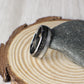 A domed tungsten men’s wedding ring crafted with meteorite and moonstone inlays, combining strength with sleek design. Packaged in a green gift box, this ring includes fast shipping, a warranty, and an exchange form for free resizing if needed.