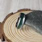 Elegant men’s tungsten ring with a domed profile, showcasing crushed malachite and shimmering moonstone inlays. The malachite’s bold green texture contrasts with the soft, glowing finish of moonstone for a unique, nature-inspired design. Made with a comfort-fit interior, this tungsten band is strong, scratch-resistant, and designed for worry-free daily wear, making it perfect as a wedding band or anniversary ring.